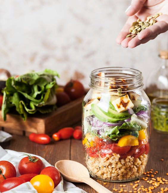 Leckere Bowl im Glas zubereitet mit Halloumi, Tomaten, Reis und Salat